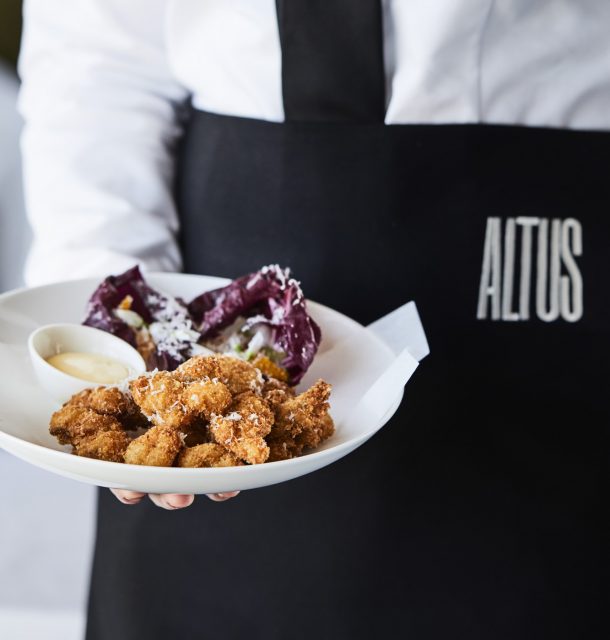 An Altus Rooftop staff member holding a plate of food