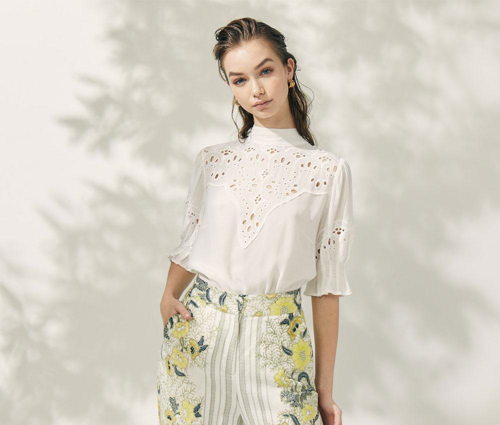 A woman wearing a cream blouse and floral skirt from OnceWas